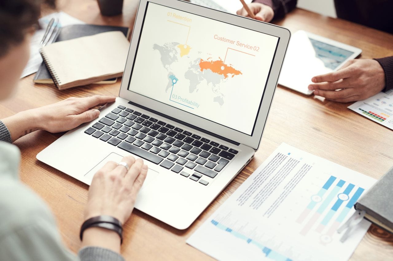 About Professional team discussing global marketing strategies with charts and graphs on a laptop.