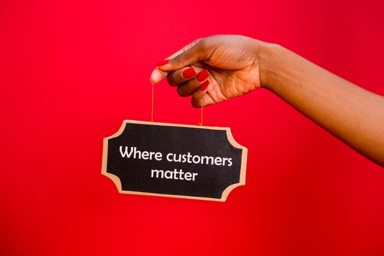 Offerings A sign with 'Where customers matter' held by a hand against a vibrant red background.