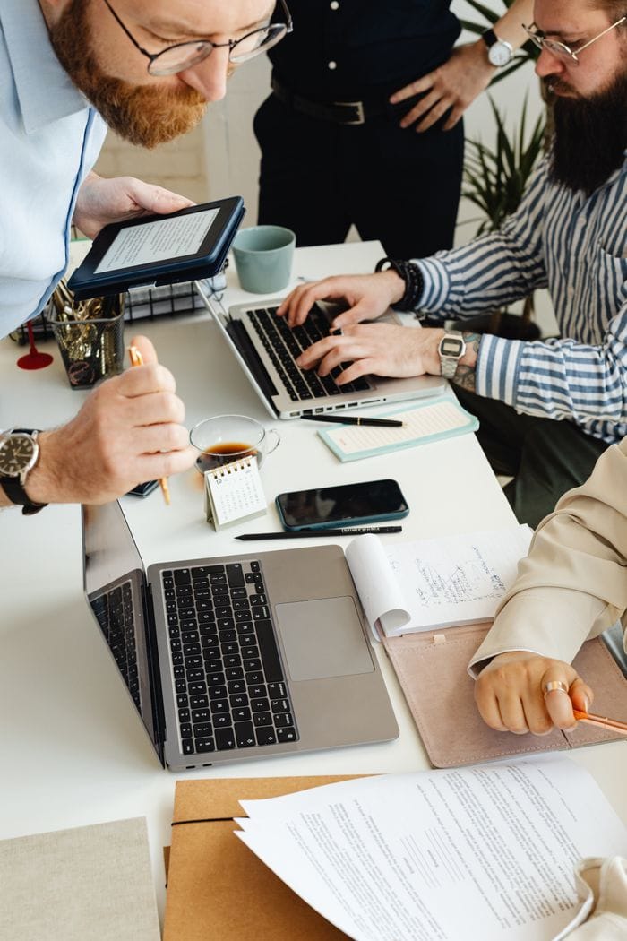Home Teamwork in action with technology, papers, and collaboration at a dynamic office desk.